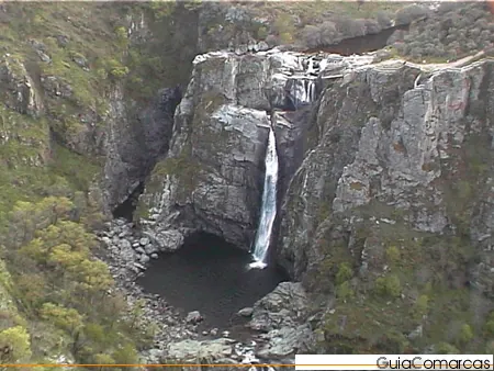 Cascada que cae a una poza entre paredes de roca