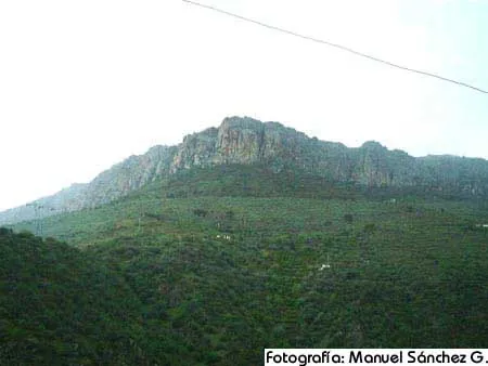 Cerro con peñascos sobre un campo verde