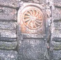 Relieve de piedra con una rosácea sobre una inscripción